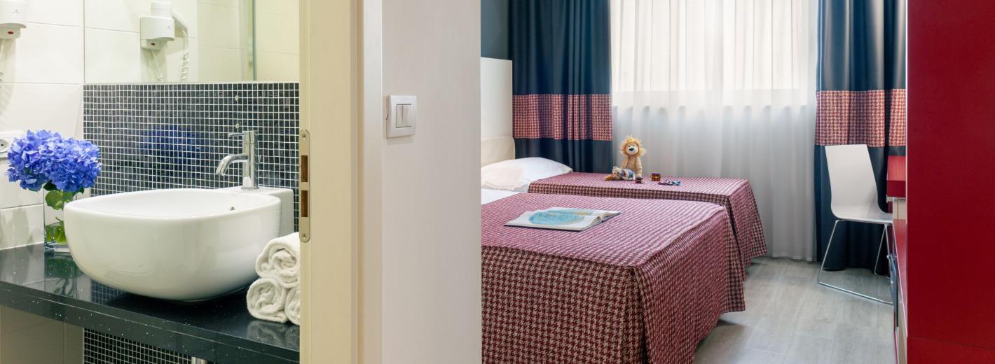 Habitación acogedora con baño, flores azules y camas ordenadas.