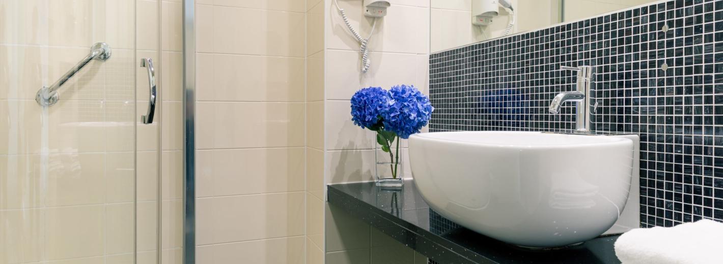 Baño moderno con flores azules y detalles elegantes, ambiente sereno y refinado.